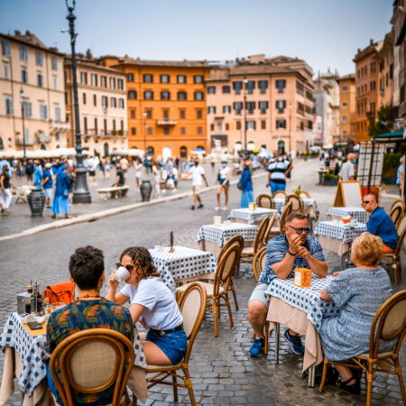 Rome, Italy, June 19 -- Some tourists enjoy life and an Italian-style breakfast sitting in a sidewalk cafe in Piazza Navona, in the historic and baroque heart of Rome. Piazza Navona is much loved by tourists and residents for the presence of numerous typical restaurants and for the monumental and artistic treasures of one of the most famous squares in the world. Image in high definition format.